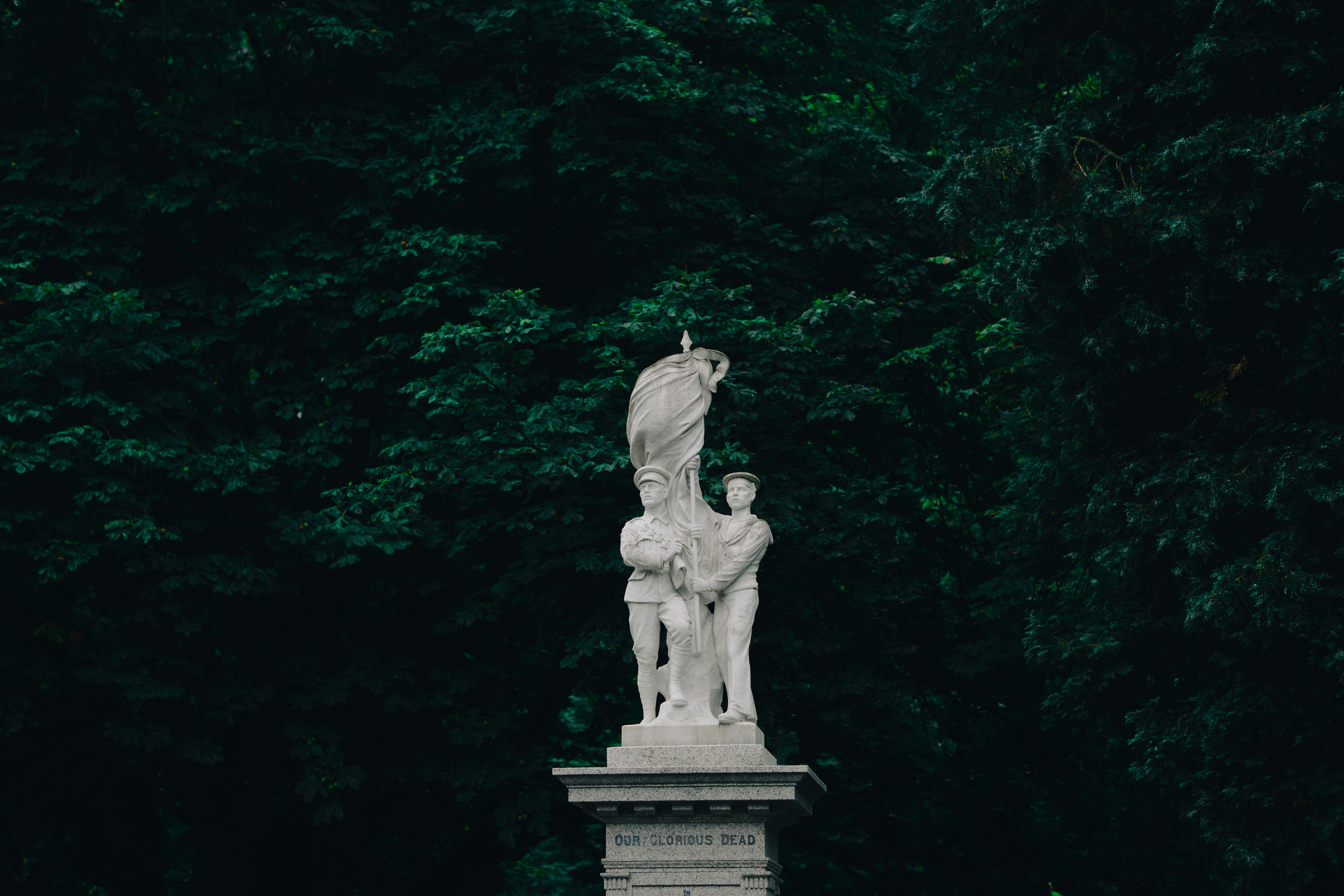 gray concrete statue in the middle of green trees